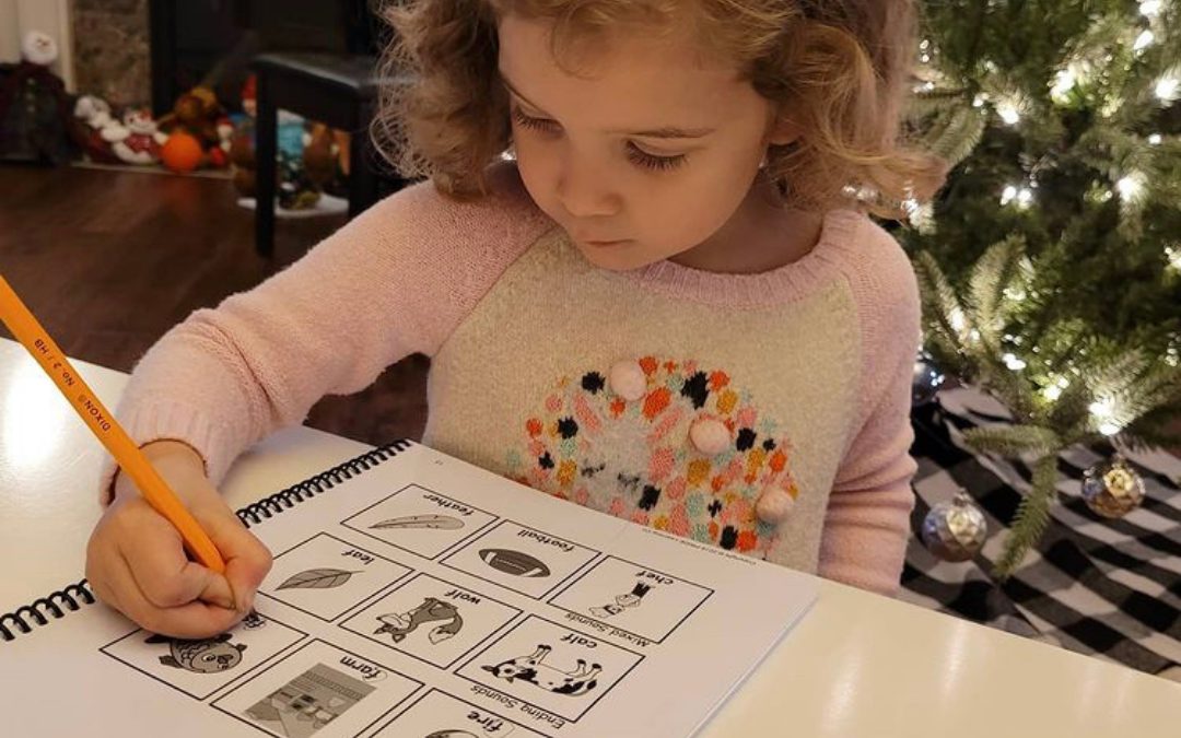 A young girl circles the letter F in a PRIDE workbook